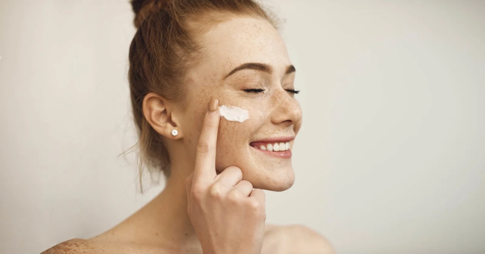 mujer aplicando crema en su rostro