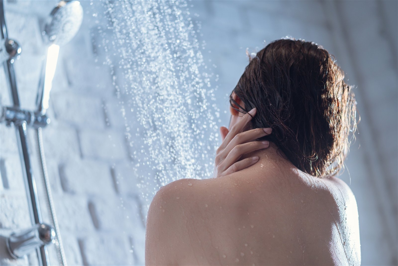 mujer lavandose el pelo en una ducha
