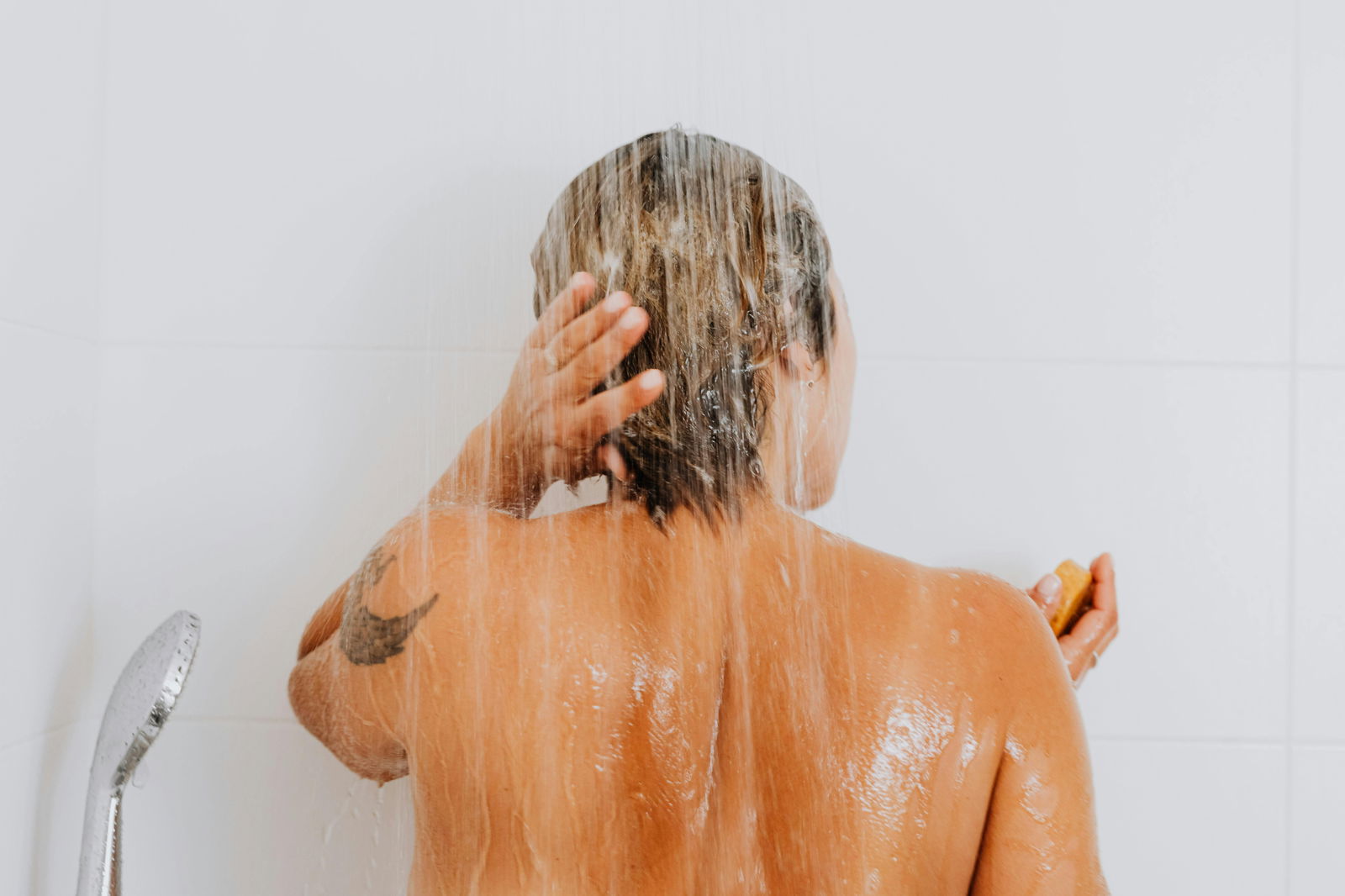 mujer lavandose el cabello en la ducha