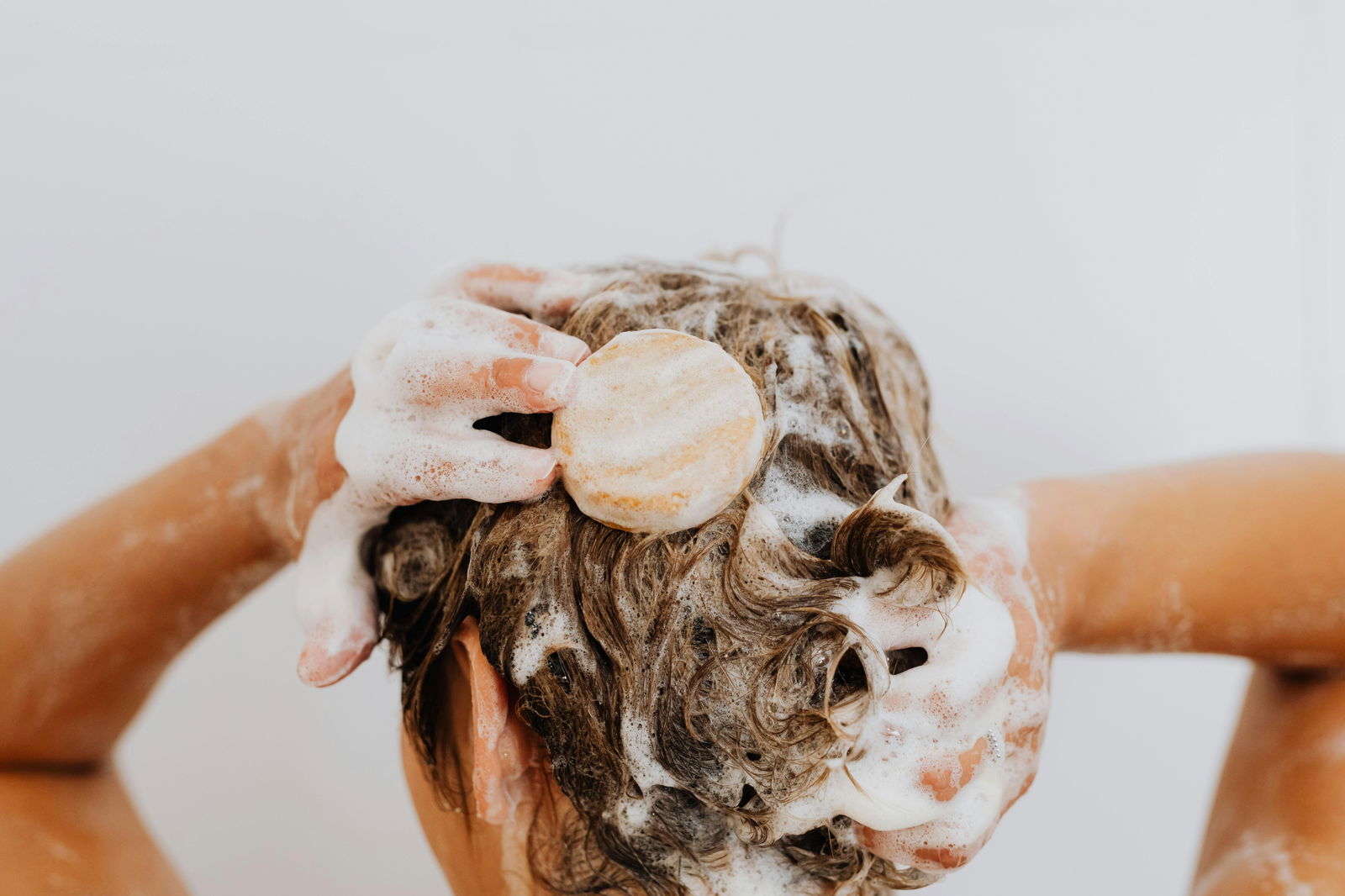 mujer usando champu solido en la ducha