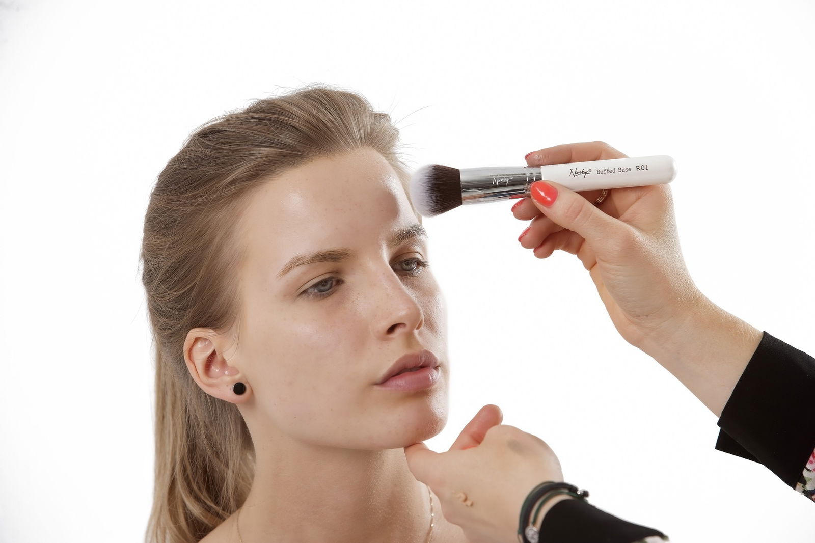 mujer aplicando base de maquillaje con brocha