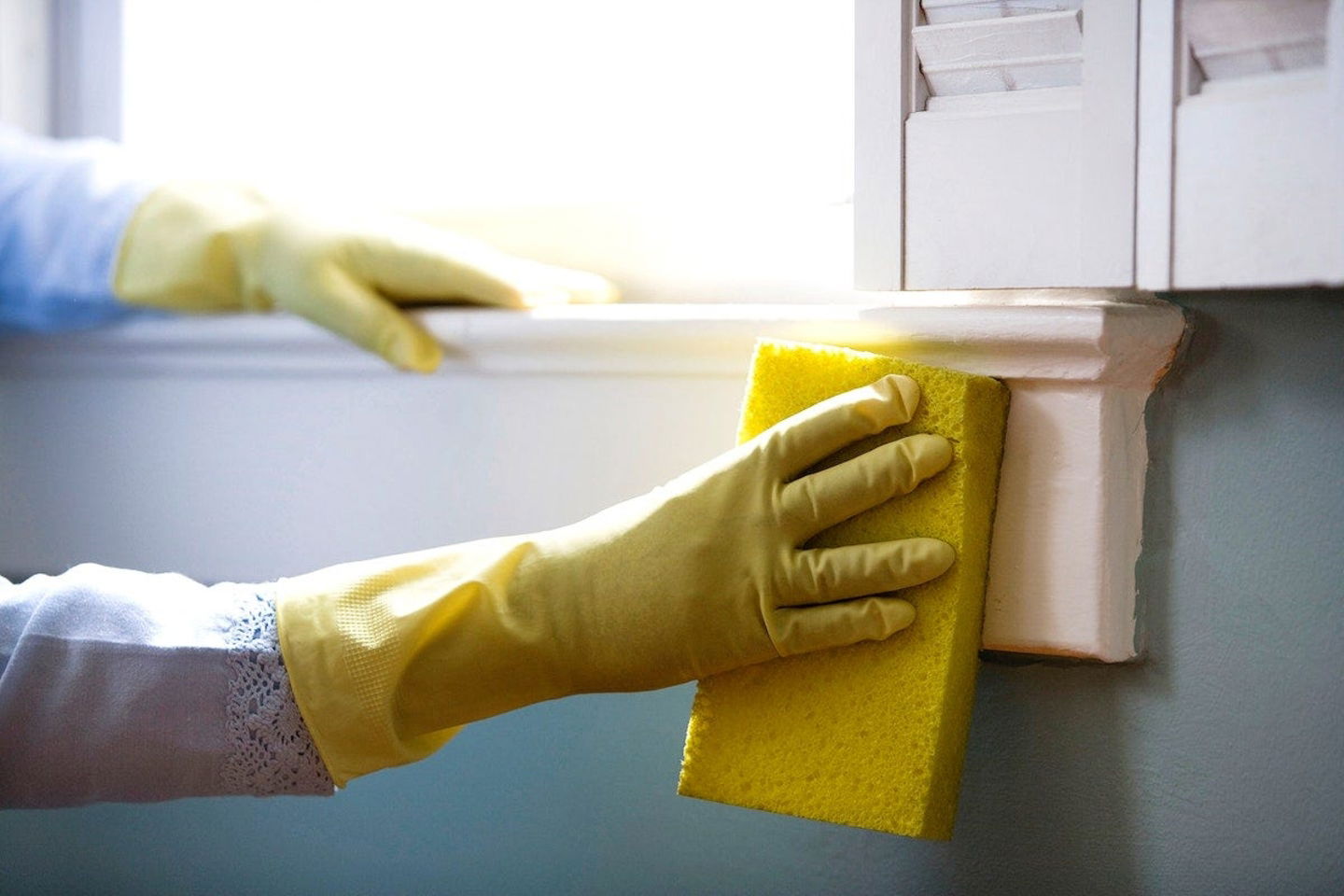 persona limpiando una ventaja con una esponja y guantes