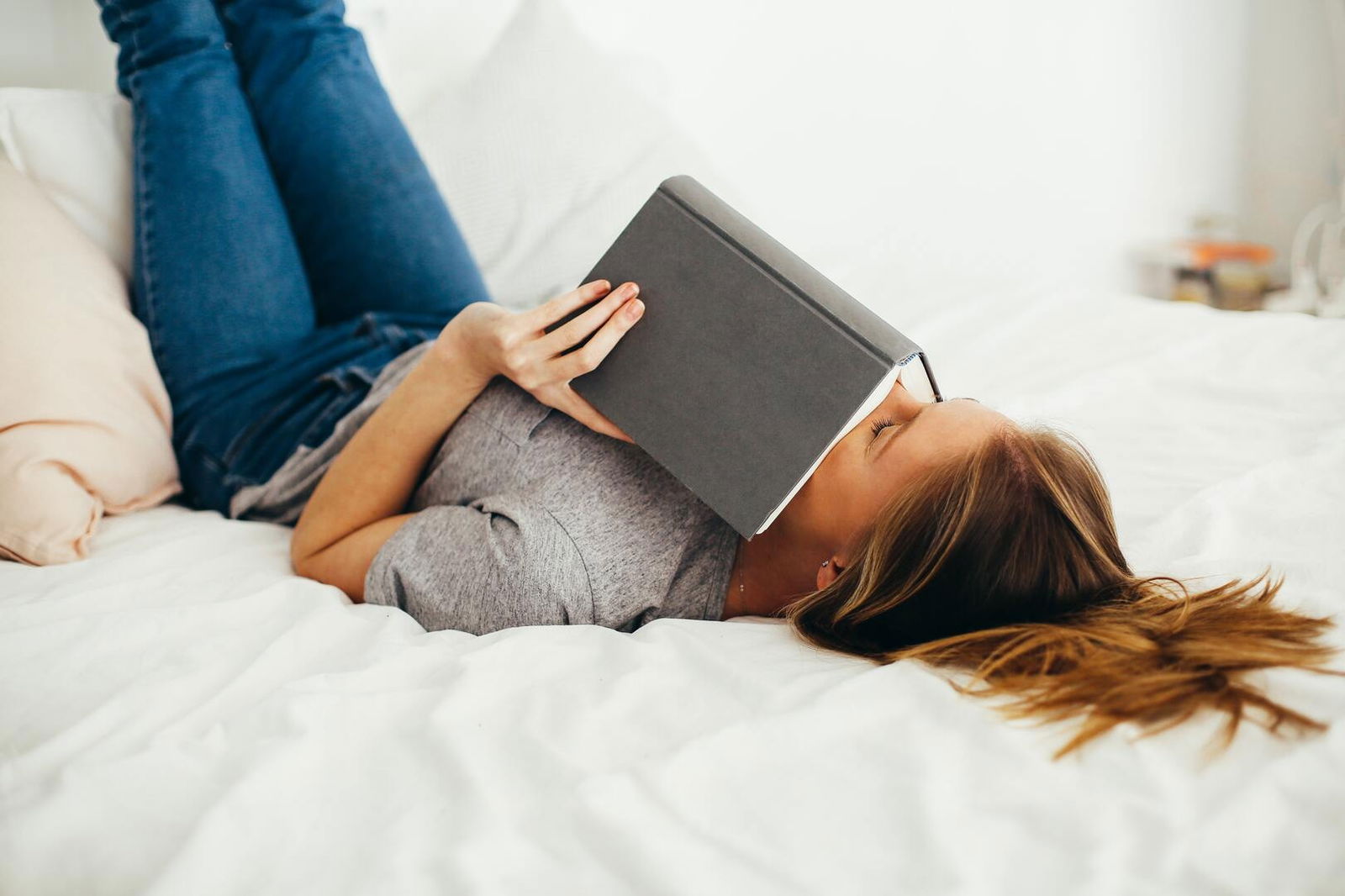 mujer con un libro en la cama