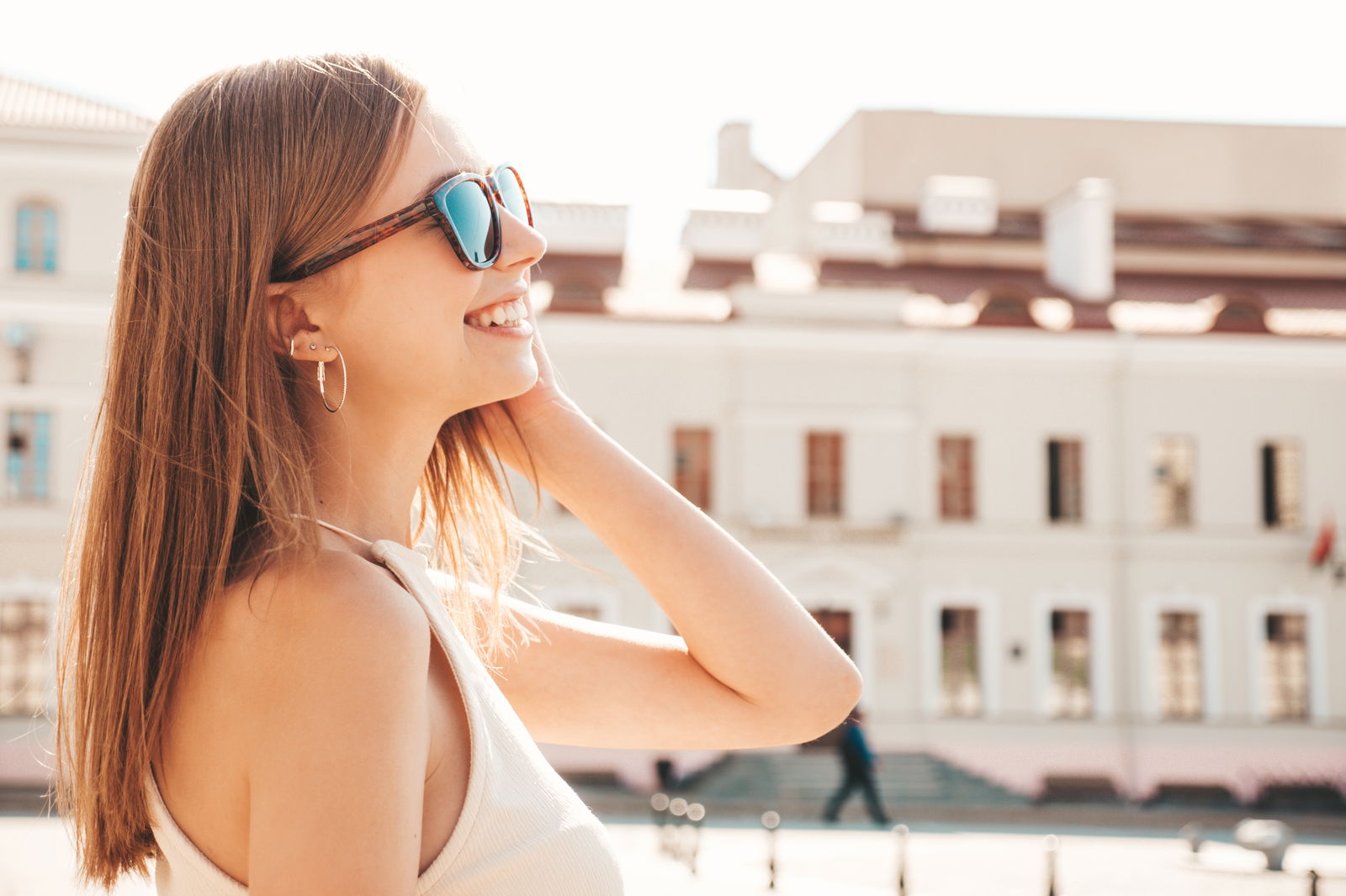 Mujer joven al aire libre con gafas de sol, disfrutando del sol de forma segura para proteger la piel