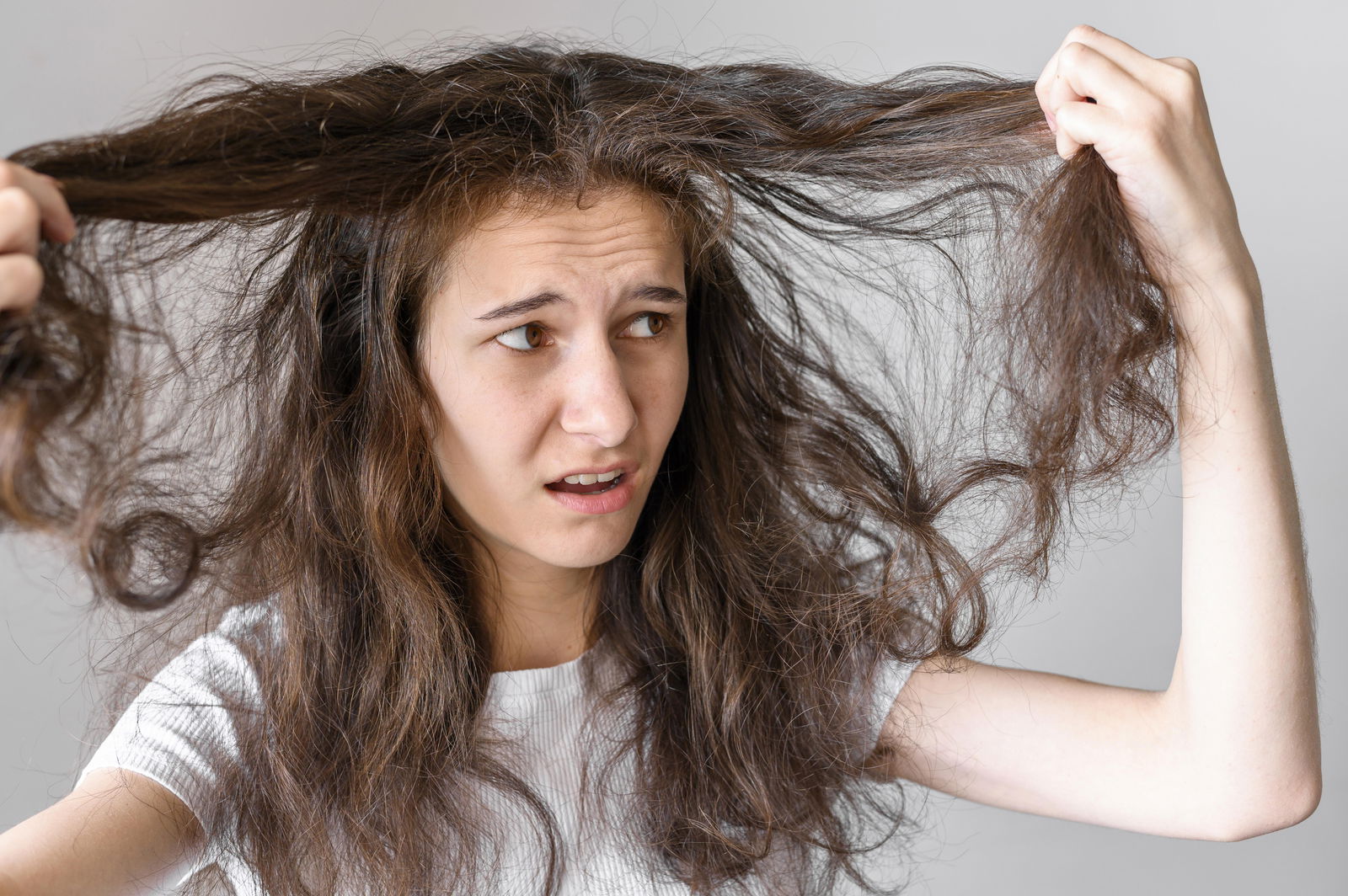 Mujer con cabello encrespado y expresión preocupada, mostrando signos de daño capilar.