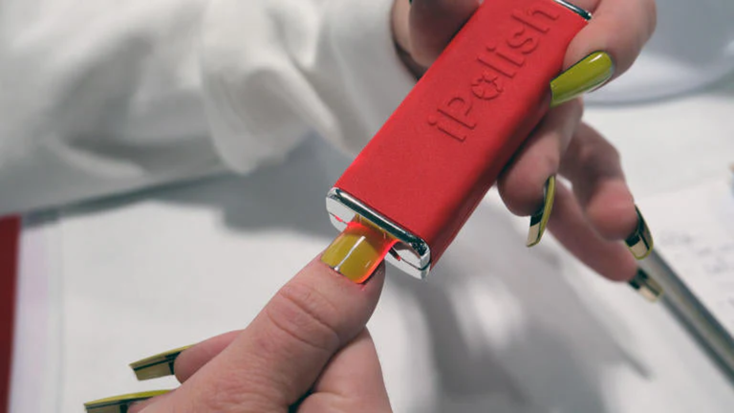 Dispositivo portátil de iPolish aplicando el cambio de color en una uña postiza