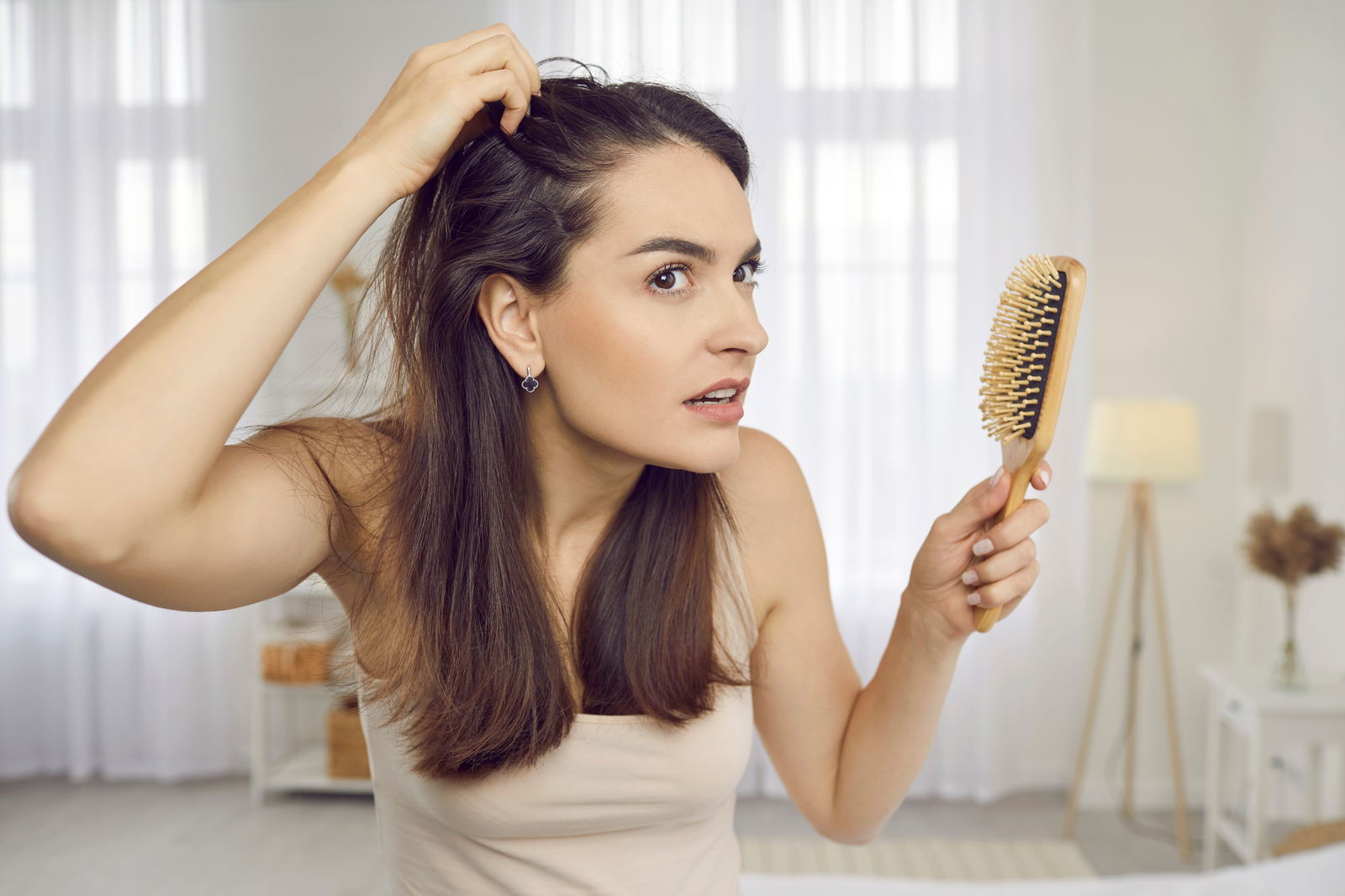 Mujer revisando la caída del cabello al cepillarse frente al espejo